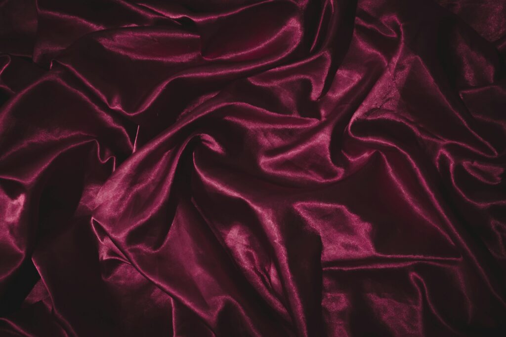 pexels photo 9441541 9441541 Luxurious burgundy satin fabric with smooth, shiny folds creating an elegant texture.